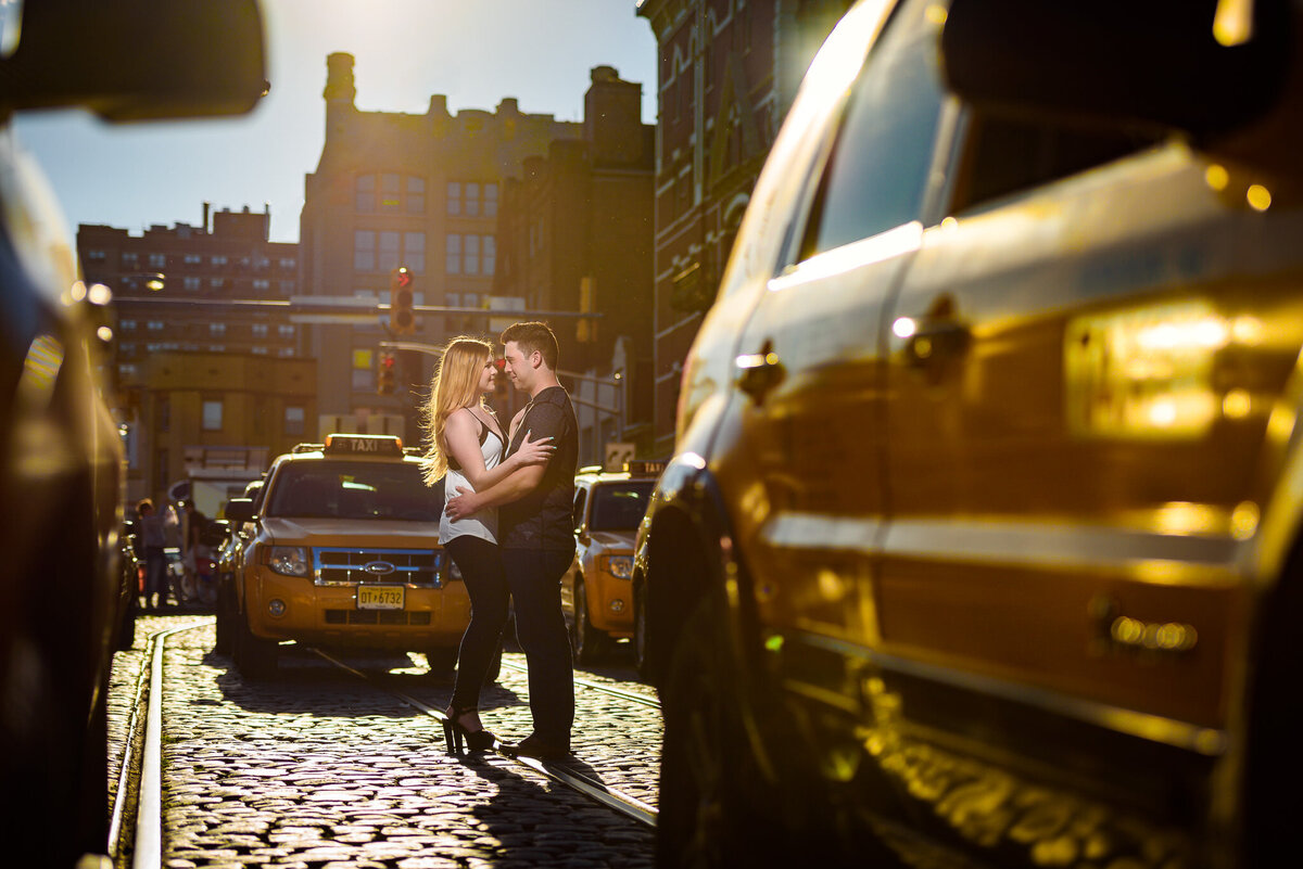 A couple embraces in the middle of a street with cars going by