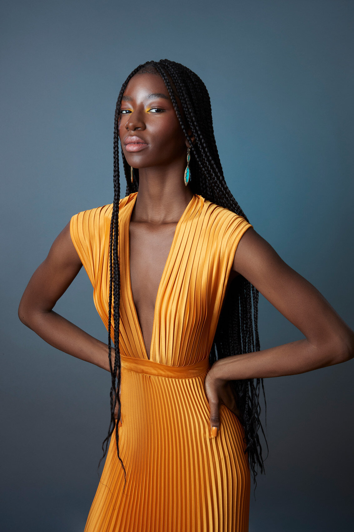 Striking portrait of Tracy in a vibrant yellow dress against a dark background, exuding elegance, captured by Ylva Erevall.