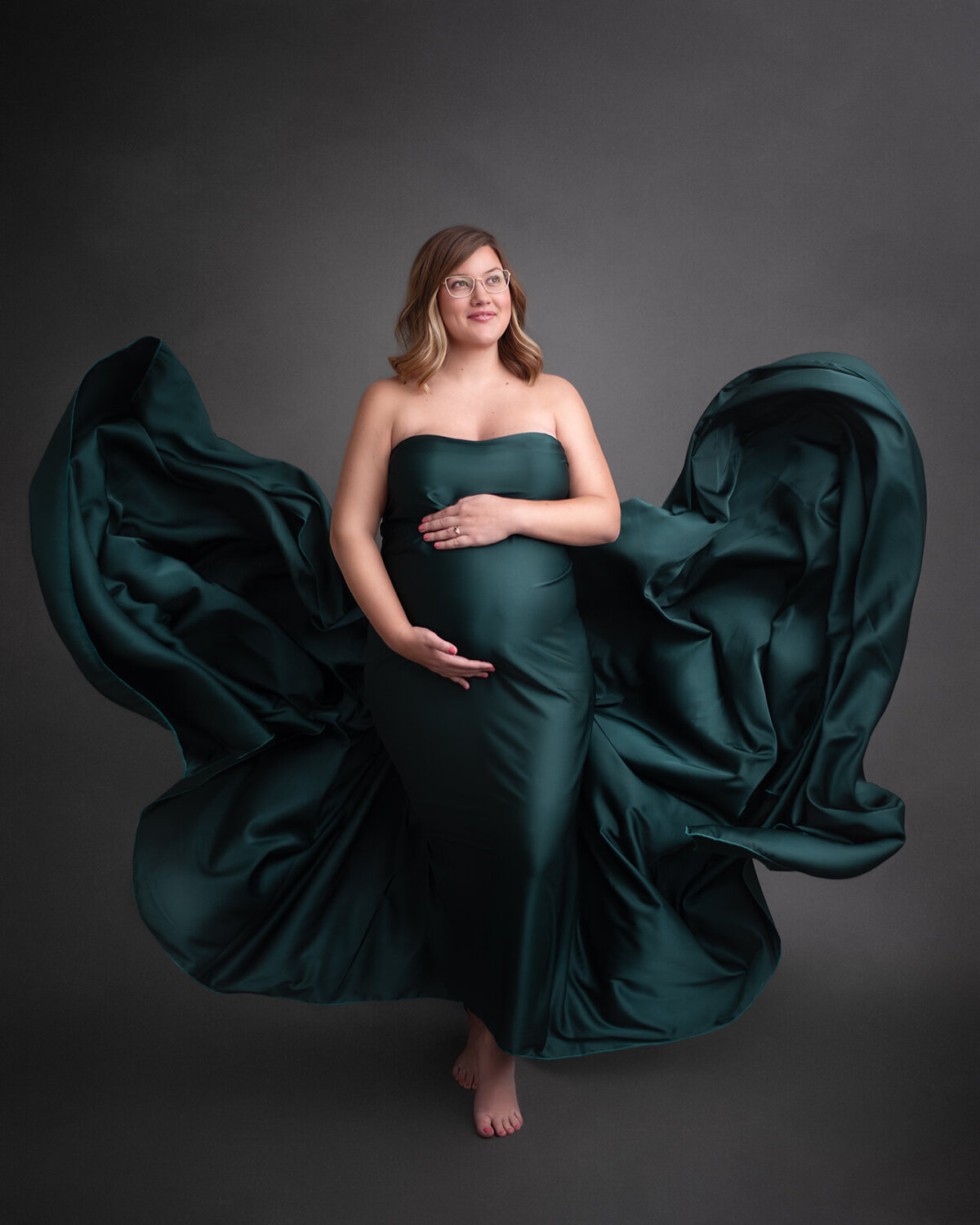 pregnant mom with green tossed fabric at maternity photos
