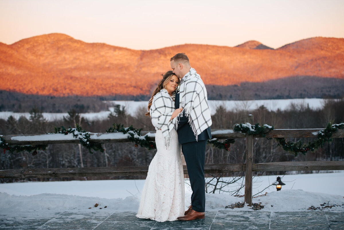 bride and groom wrapped in blanket with sunset mountain views at mountain top inn wedding chittenden vermont