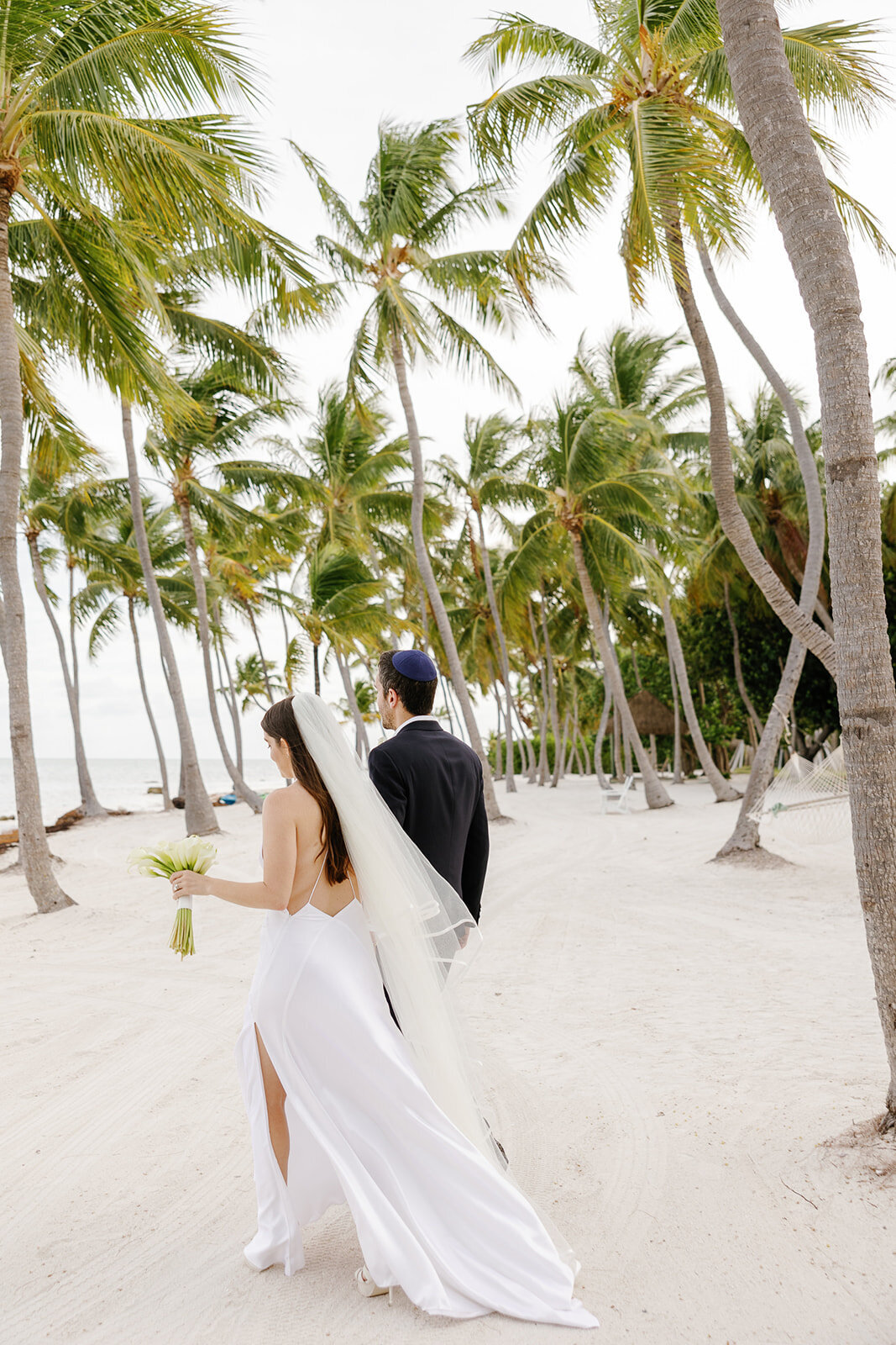 Minette and Evan walk along the sandy shores, celebrating their wedding day in the Florida Keys. Micro wedding photography by Claudia Amalia.