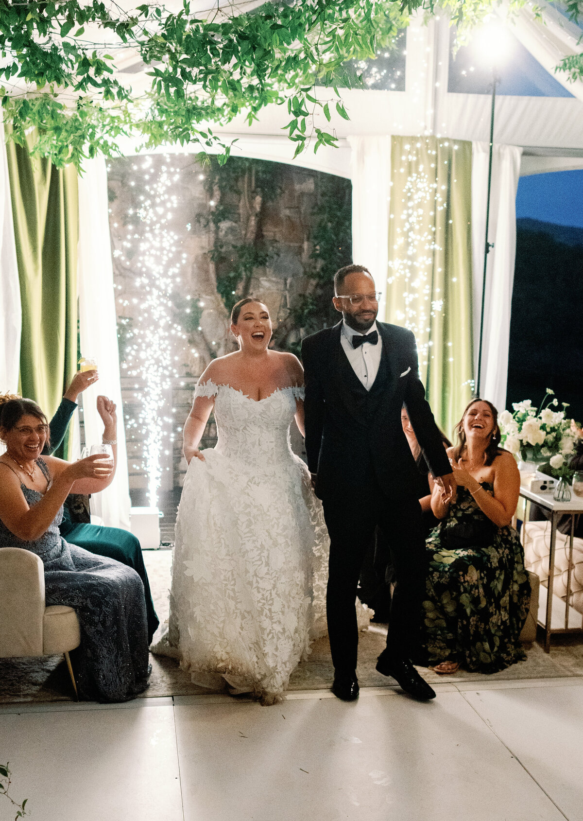 The newlyweds make a joyful grand entrance into their Castle Ladyhawke wedding reception under twinkling lights and greenery.
