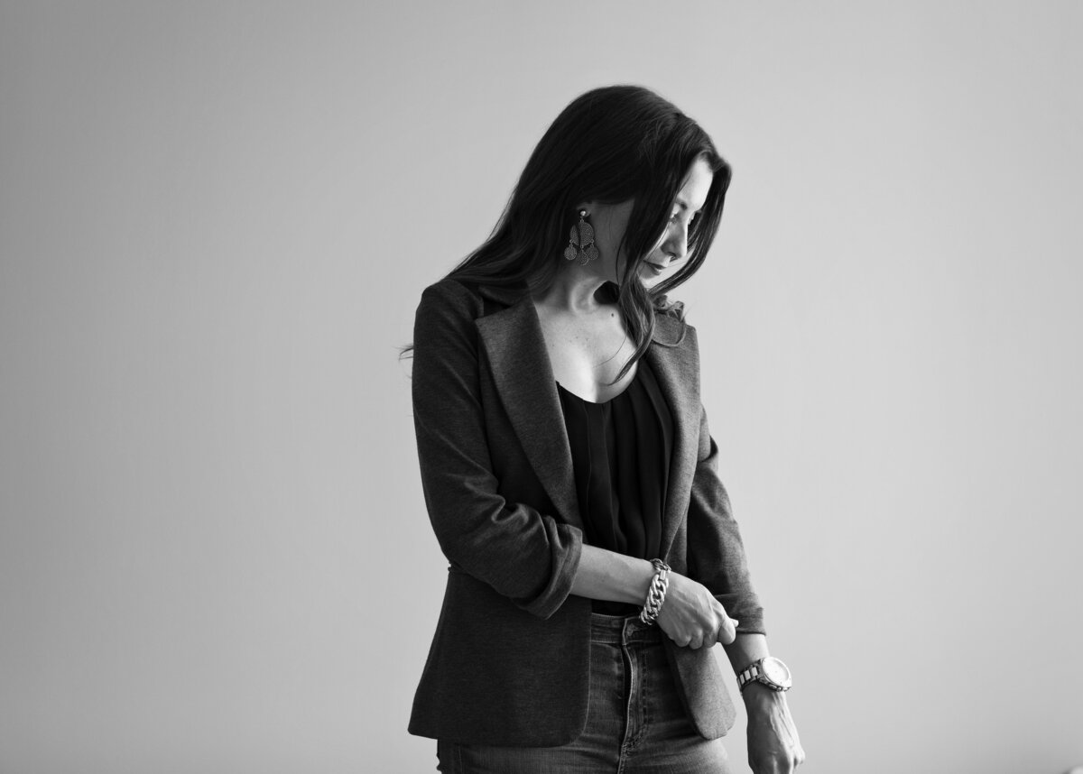 a black and white image of a woman wearing black looking off camera