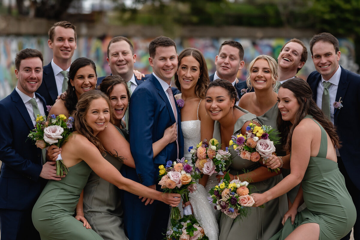 Wedding party huddles together with the bride and groom