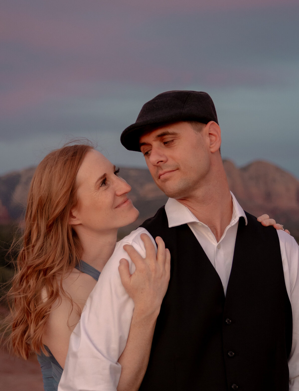 Couple standing against red rock backdrop during Sedona engagement session