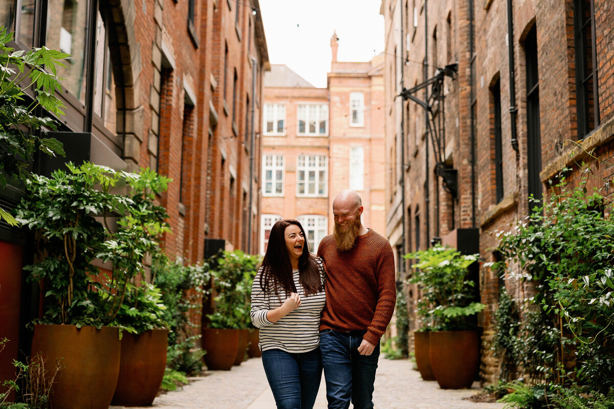 A couple walking and laughing on their engagement shoot in Kampus, Manchester