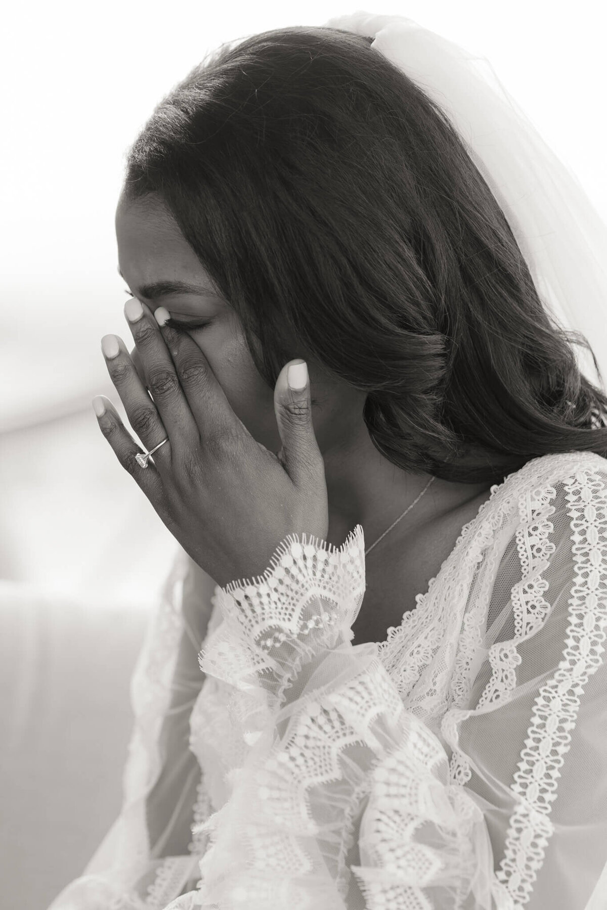 bride in lace gown wiping a tear