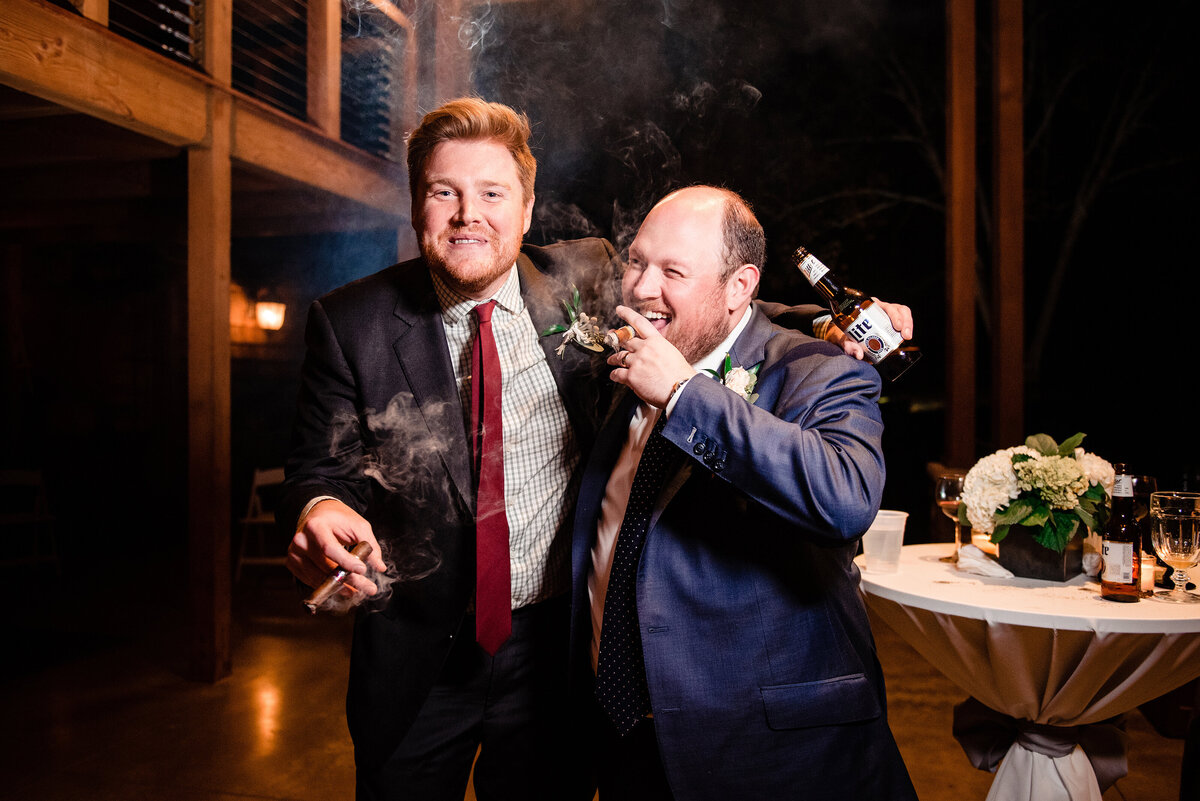 Groom with a friend smoking a cigar outside