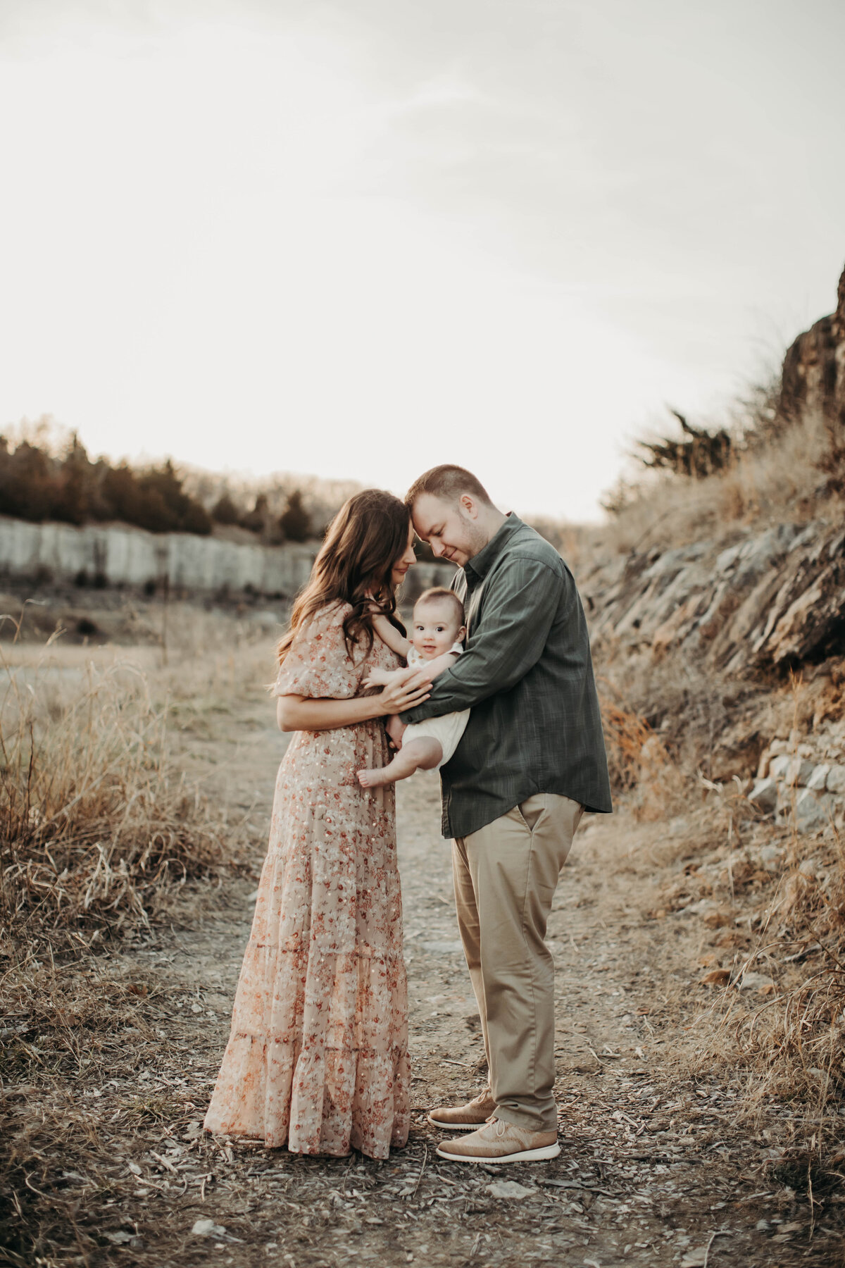 Mom and dad in close embrace with baby boy.