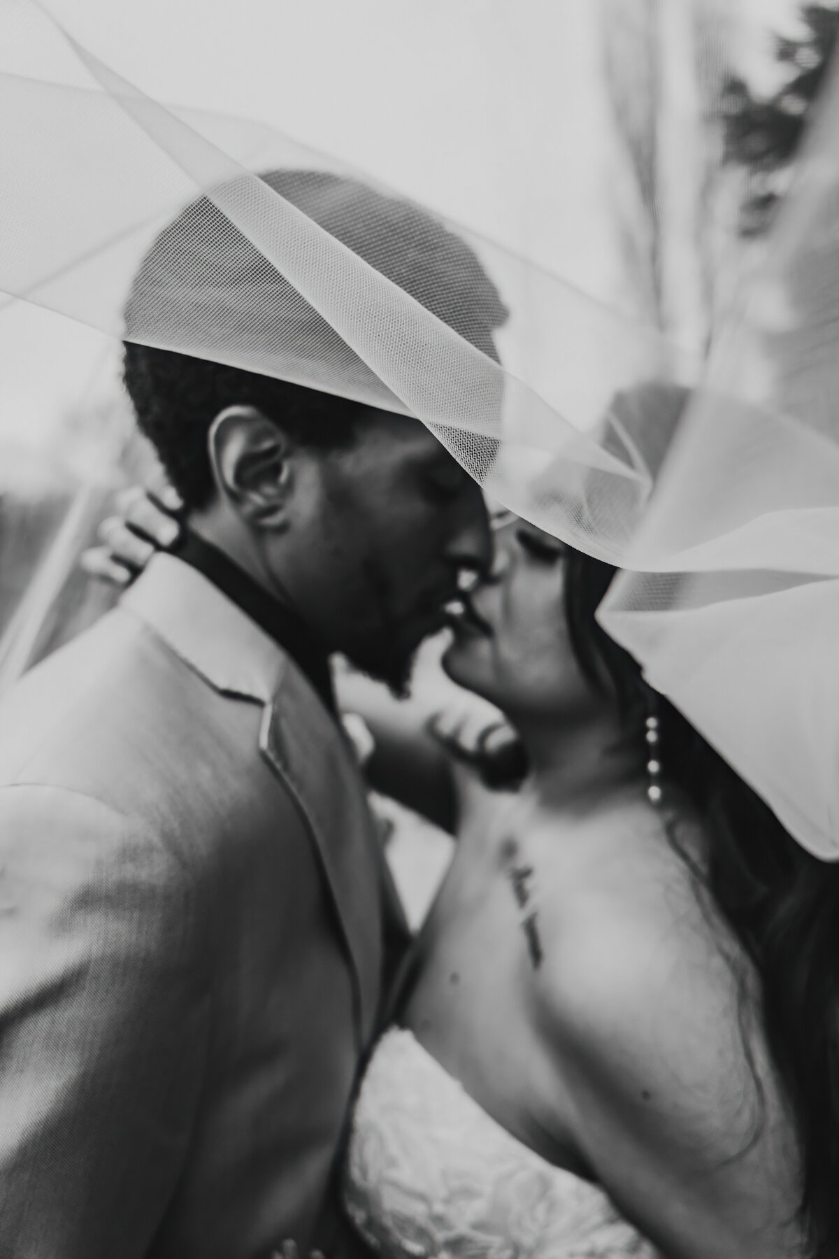 a bride and groom under the veil slightly out of focus due to the veil being in front of them