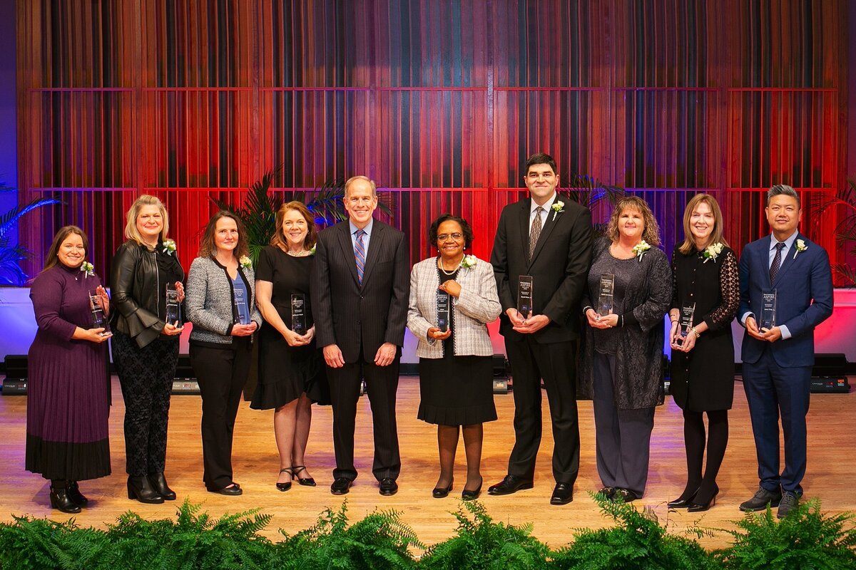 a-group-of-business-leaders-and-professionals-standing-on-stage-holding-awards-at-a-corporate-recognition-event-in-indianapolis-indiana-historical-society