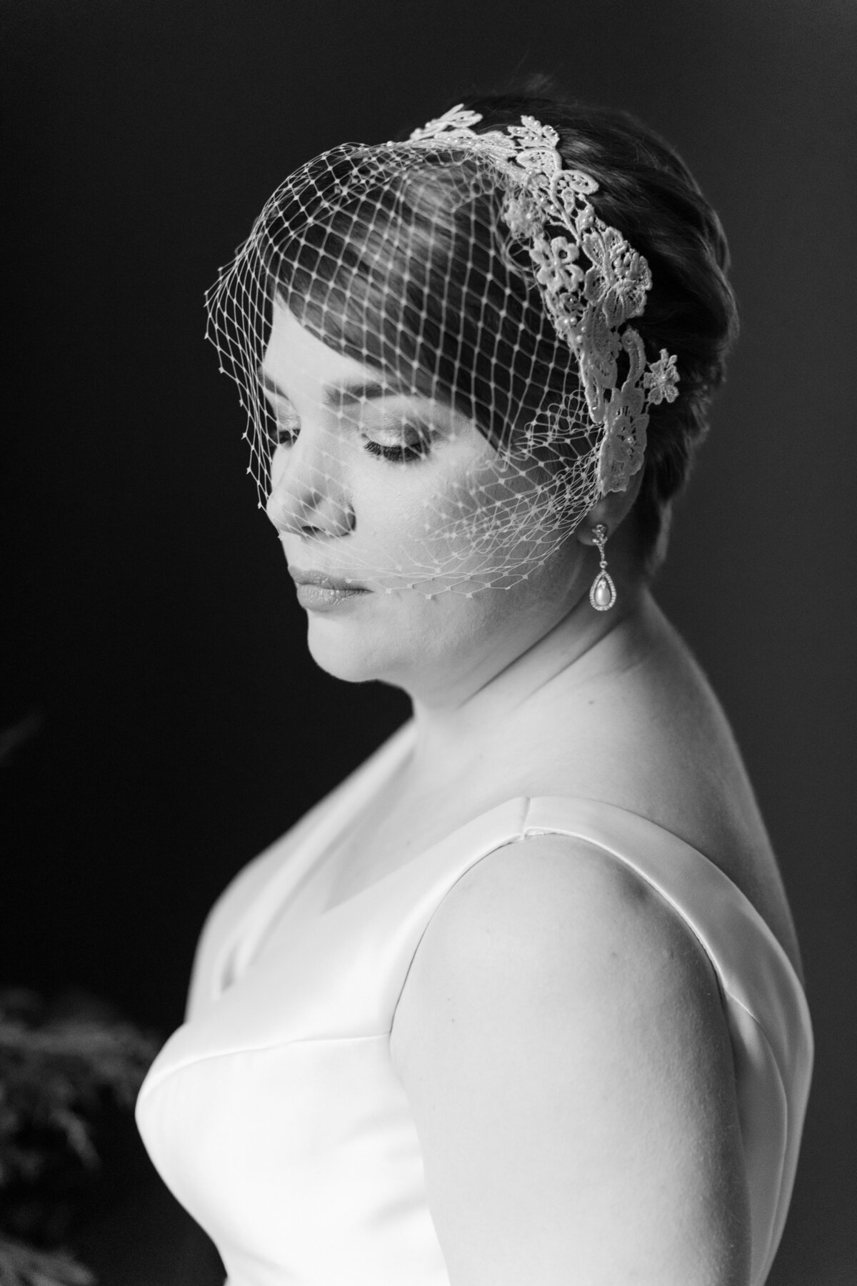 Dramatic black and white image of bride wearing birdcage veil