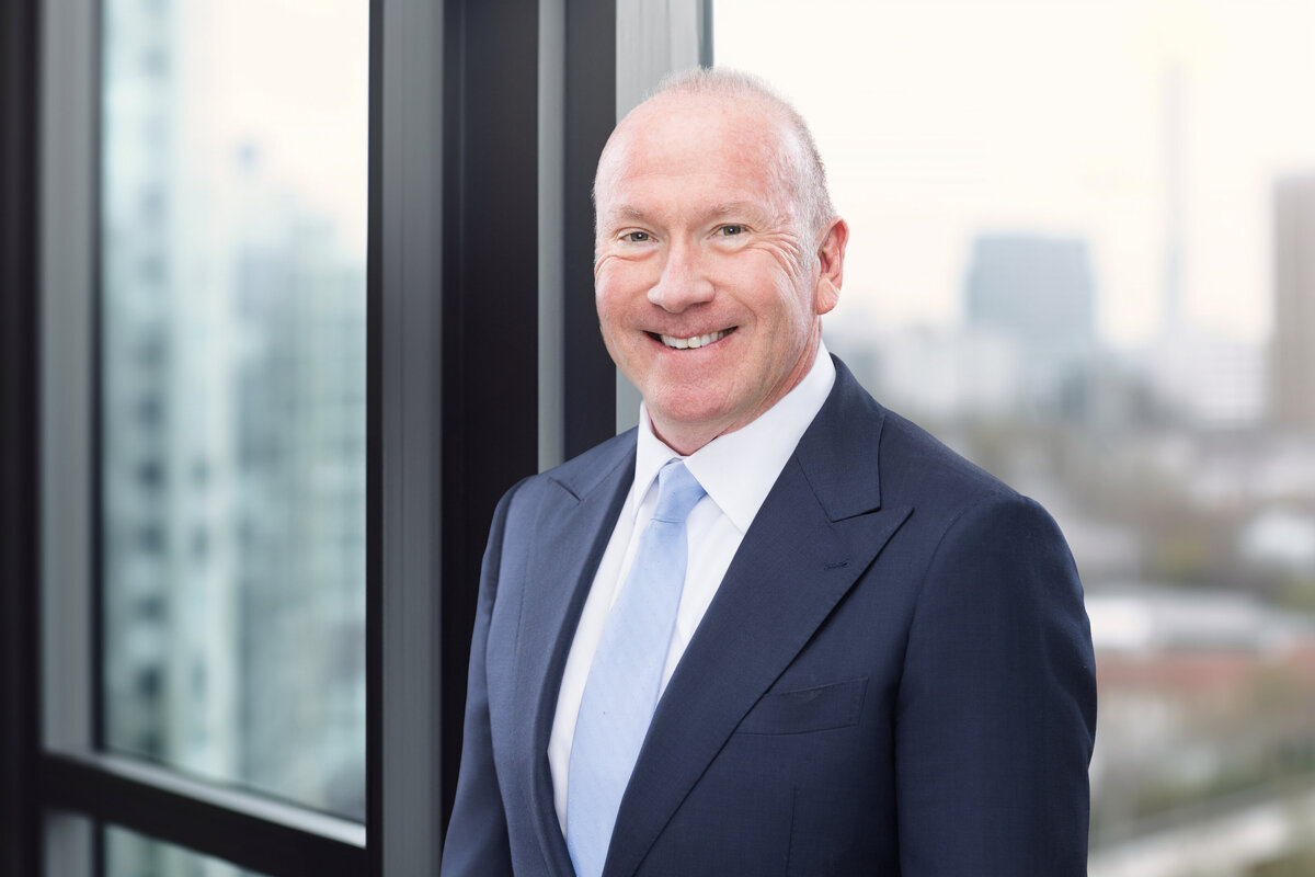 A professional headshot of a confident businessman taken in Cincinnati. The individual is captured against the backdrop of the city's skyline, showcasing the city's modern architecture.