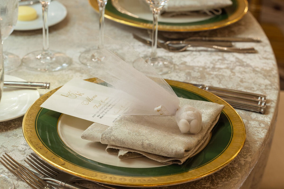 A green and gold plate with a napkin and a menu on it