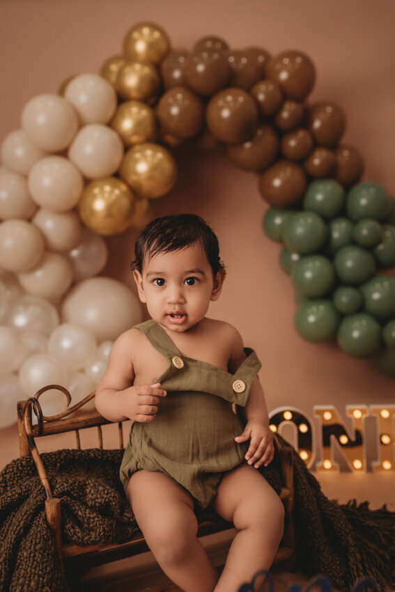 Cake smash milestone session with Atlanta, Georgia cake smash photographer. Milestone photography session with earthy tones, balloon garland and sweet baby boy eating cake for his first birthday.