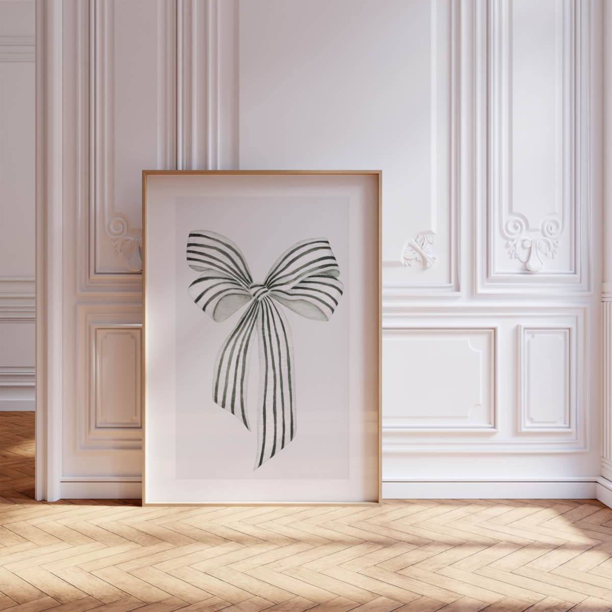 A framed artwork of a black and white striped bow by Sweet Pea Ink Creative rests on a wooden floor against a decorative white wall in a bright, elegant room.