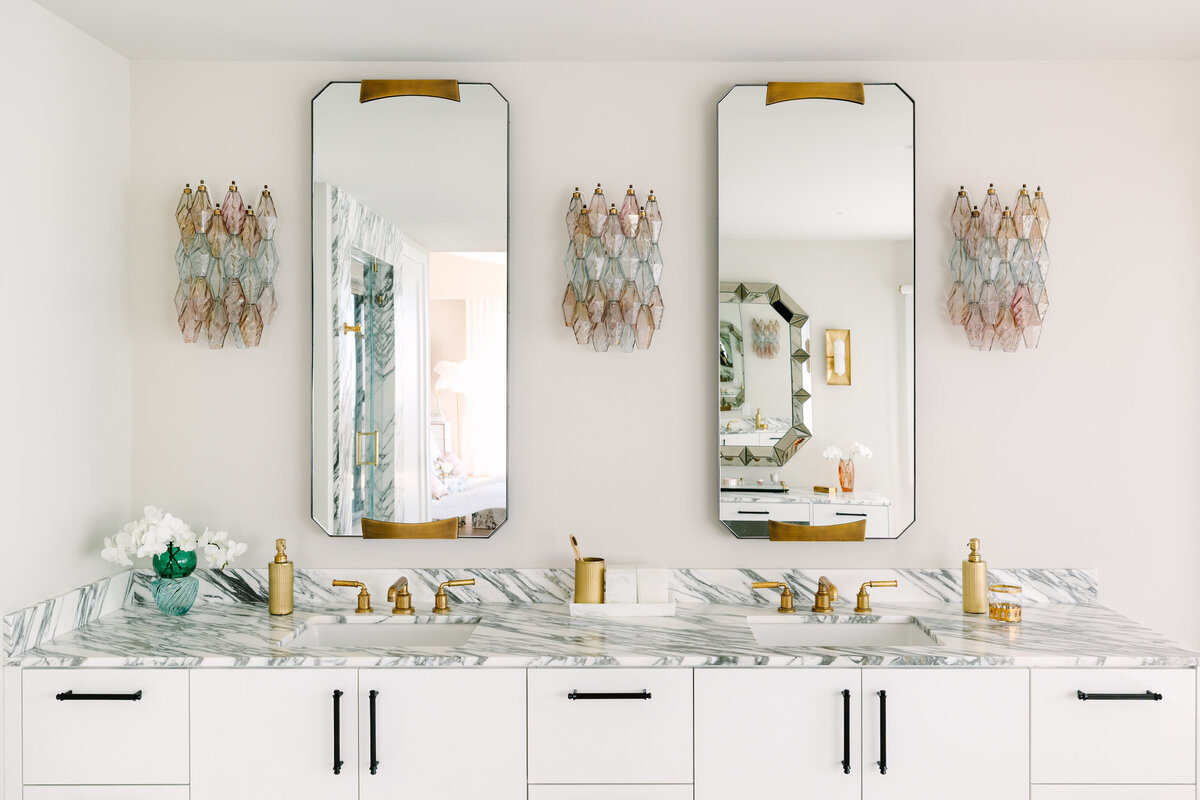 Primary bathroom with white high gloss vanity and brass base, Arabescato Corchia marble counters, and vintage Carlo Scarpa Venini sconces.