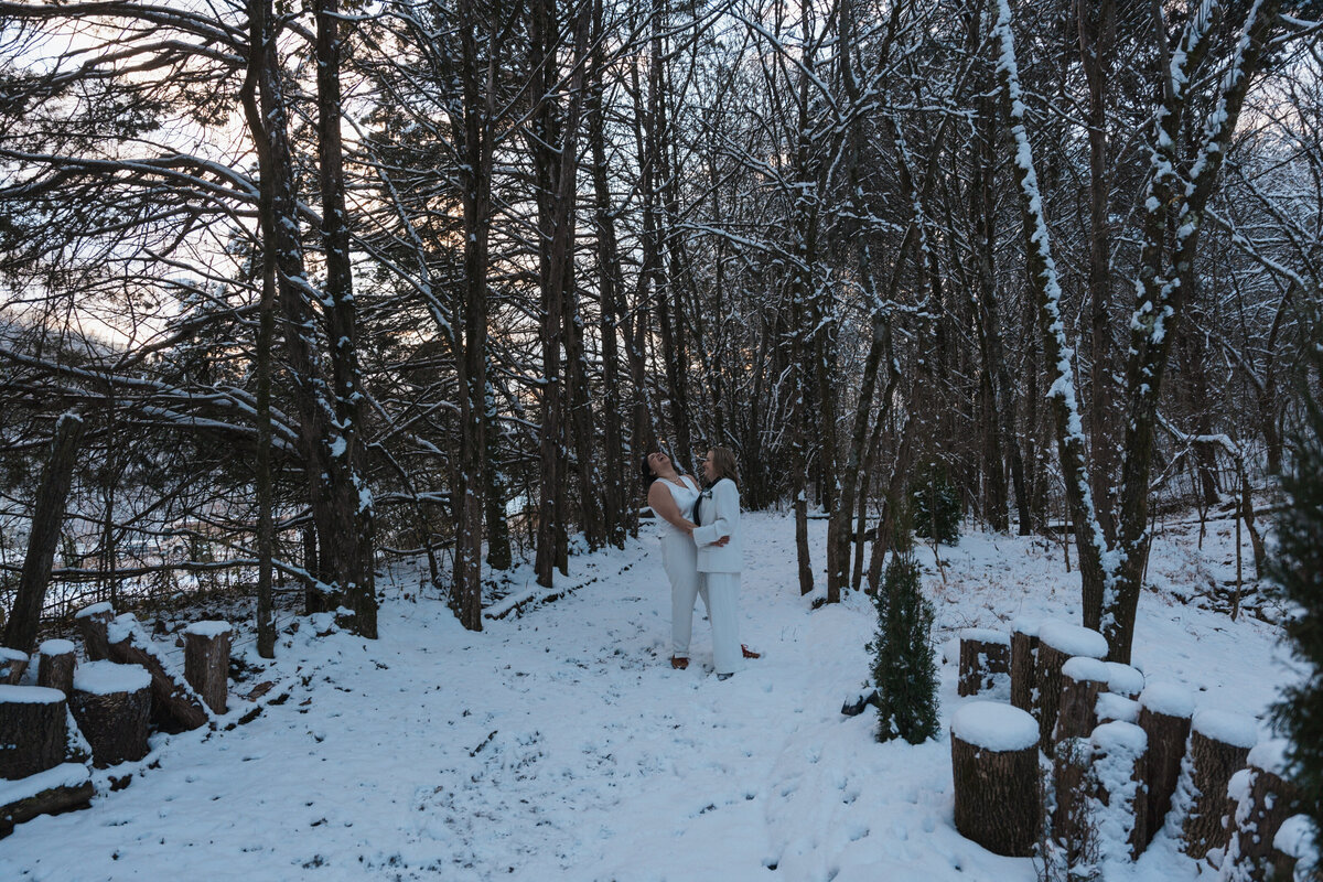 Women stand beneath snow-filled trees  