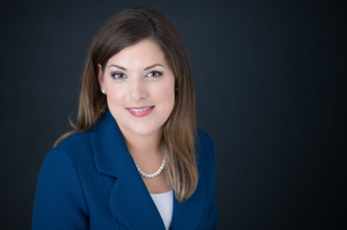 classic headshot of female lawyer in blue suit jacket and pearls
