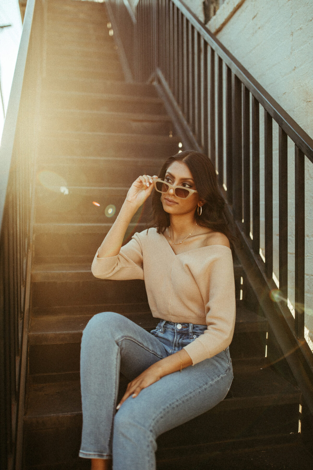 High school senior with vintage style wearing sunglasses and sitting on a black staircase downtown