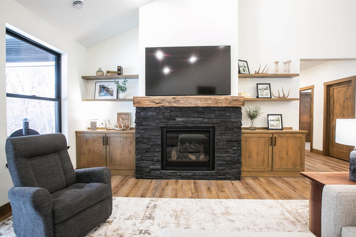 Cozy living room in Elk River custom home with fireplace, built-ins, and large windows