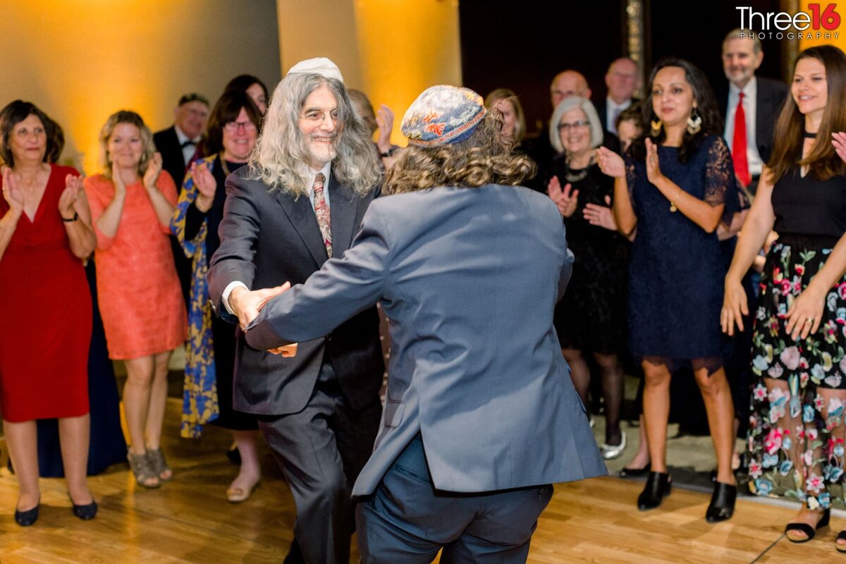 Two men dance a traditional Jewish dance at wedding reception