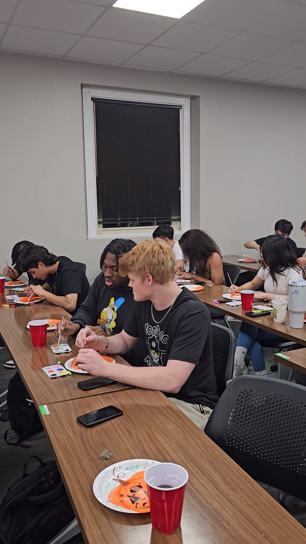 The group of boys sits around a rectangular wooden table, immersed in crafting their art pieces at Soleil Vida Studio's workshop.