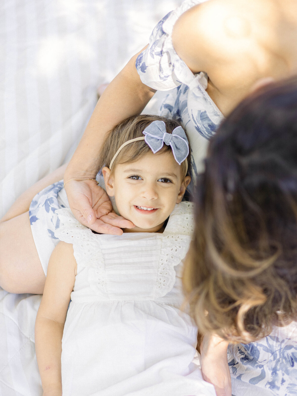 Daughter laying in mother's lap outside their home in Cranford, New Jersey during a family photography session.