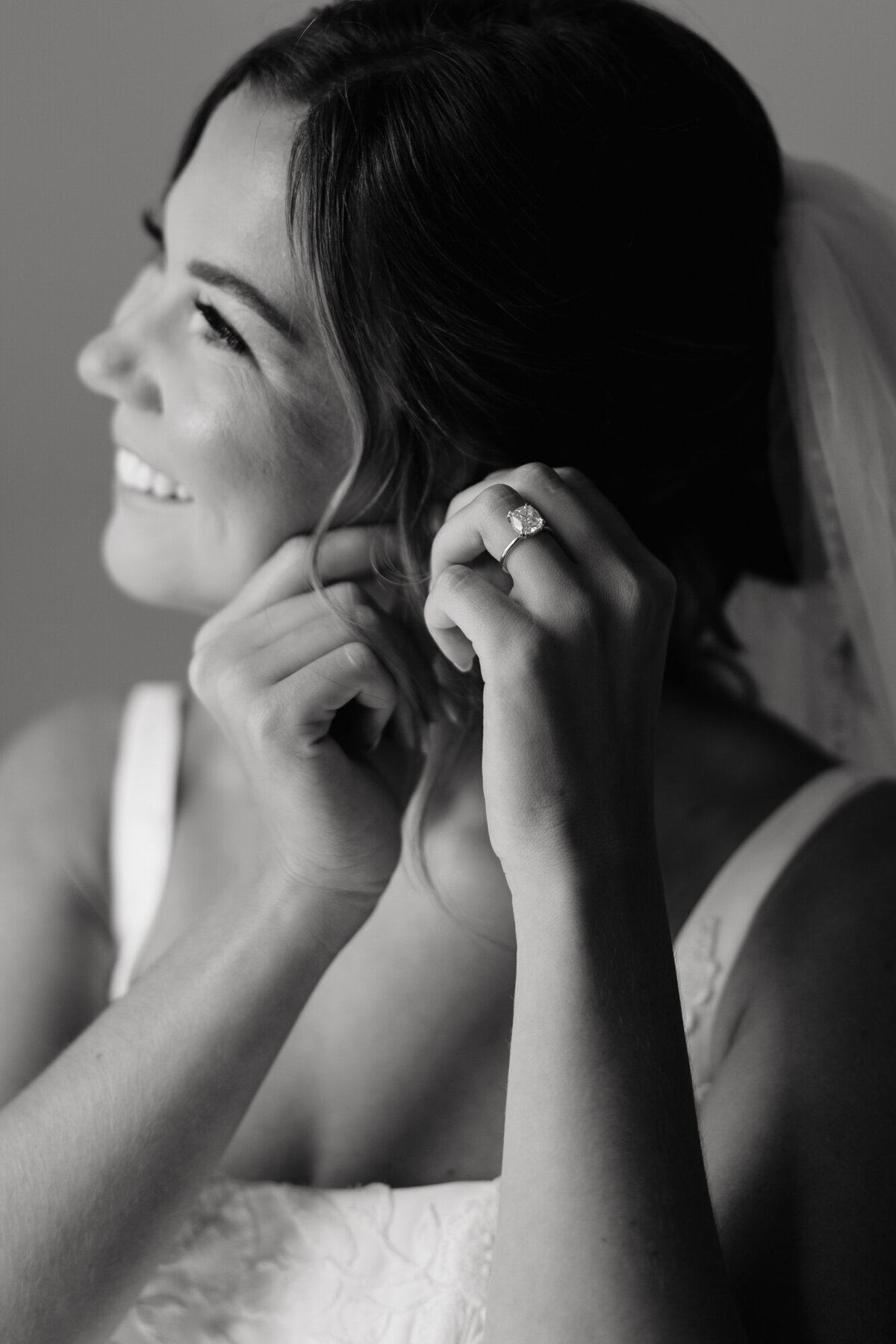 Nicole smiling while putting on earrings before ceremony