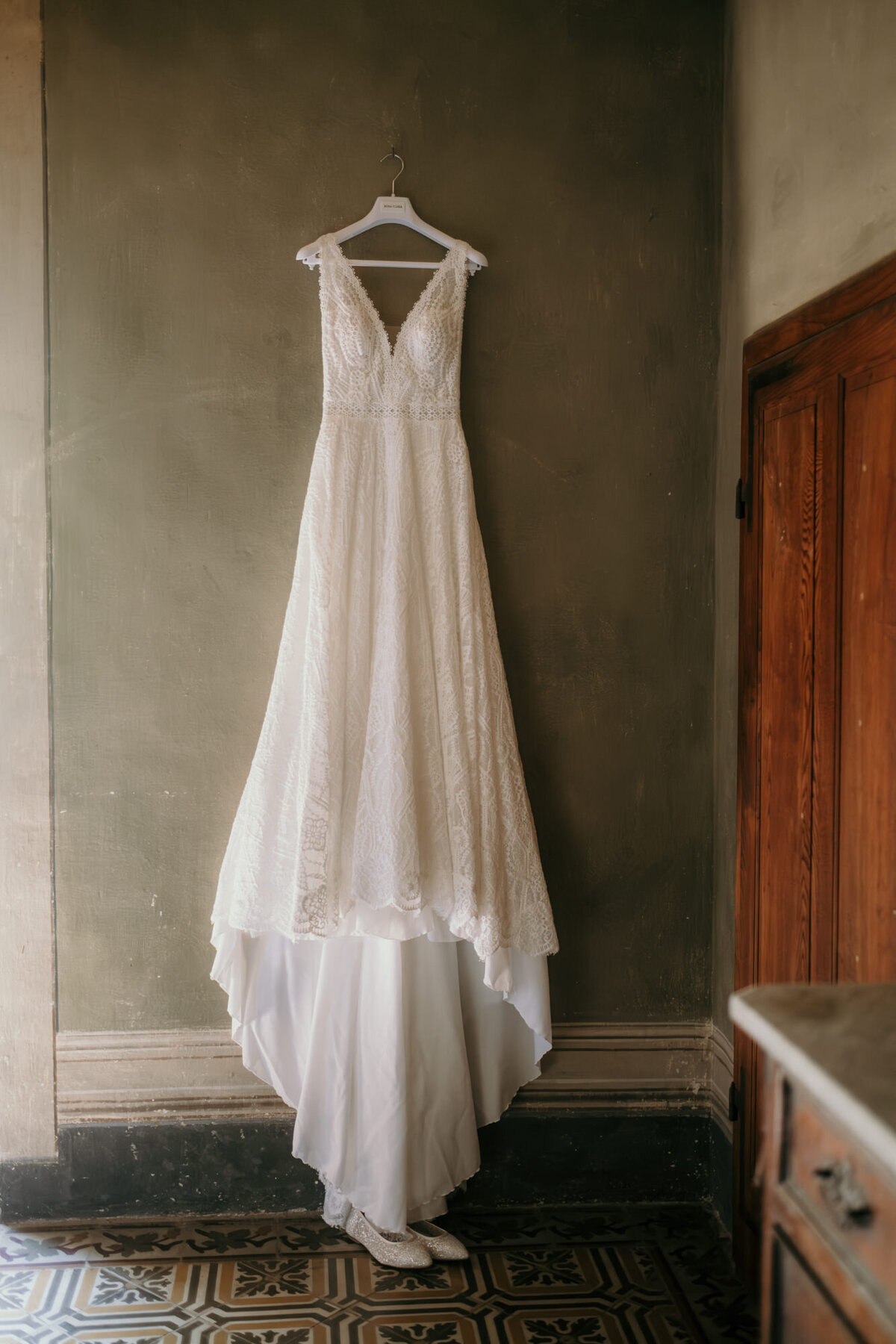 Detailshot of the wedding dress hanging on a wall.