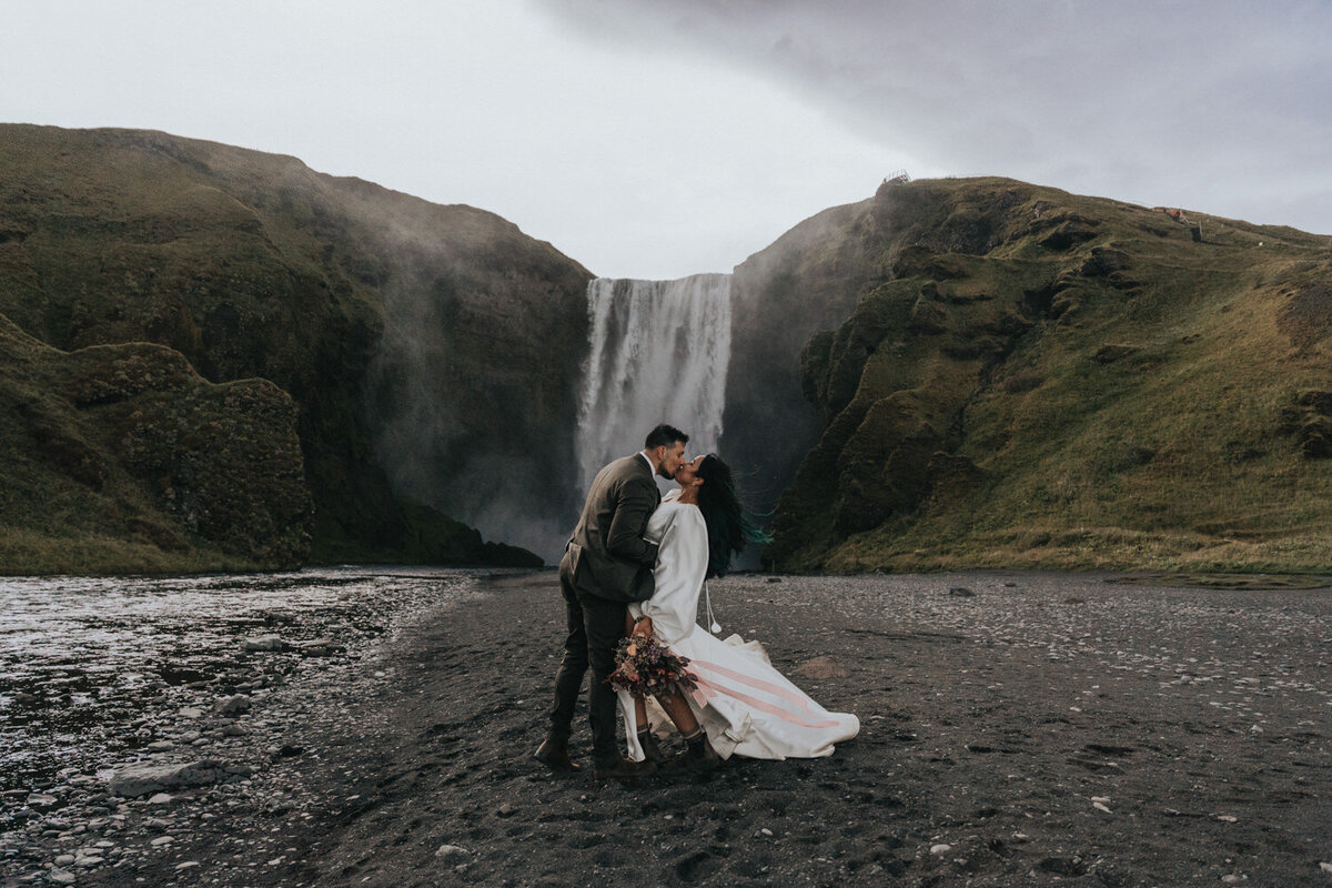 Near a secluded waterfall, a husband and wife share a loving kiss 