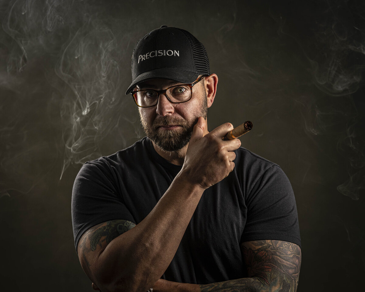 Headshot in CT of man in black shirt and Precision hat, arms crossed, with tattoos visible, by Rob Faber Photography.