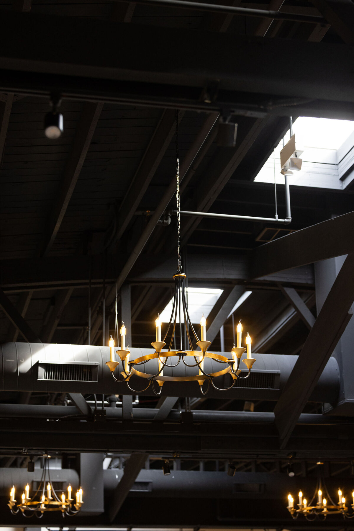 Close-up of the romantic and timeless chandelier scattered throughout the Locus and Happy Hour space, adding elegance and attention to detail within original exposed industrial ceilings and natural light