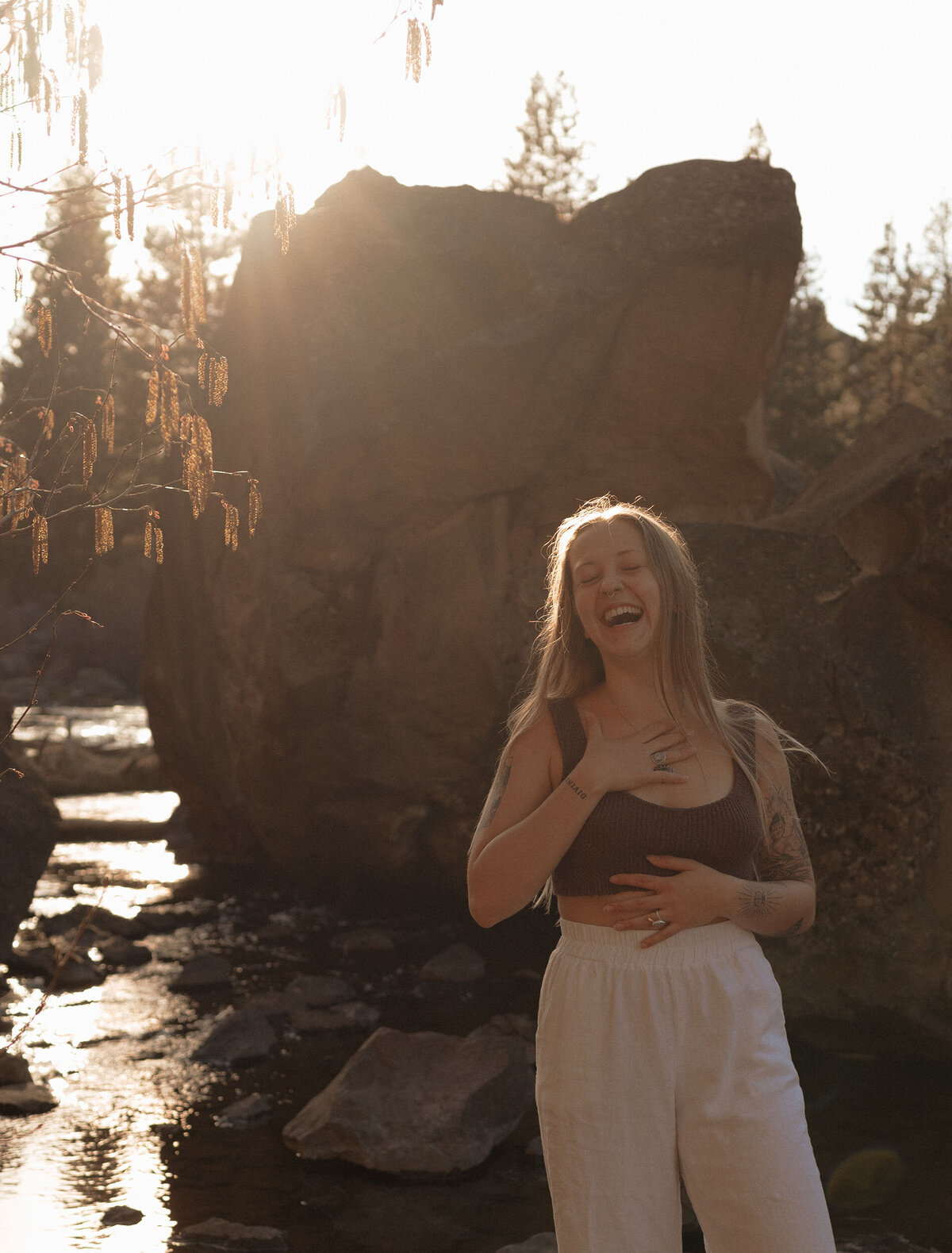 female entrepreneur laughing in front of river rocks during golden hour in central Oregon