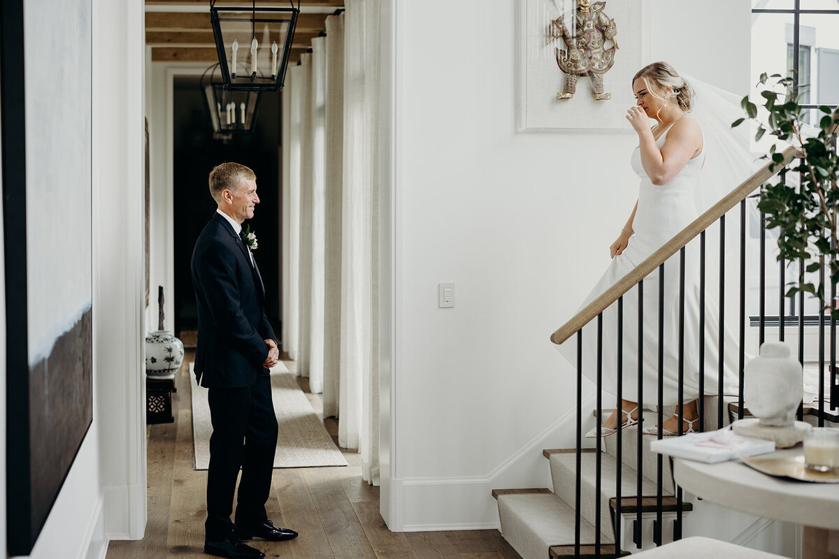 Bride comes down the staircase to dad