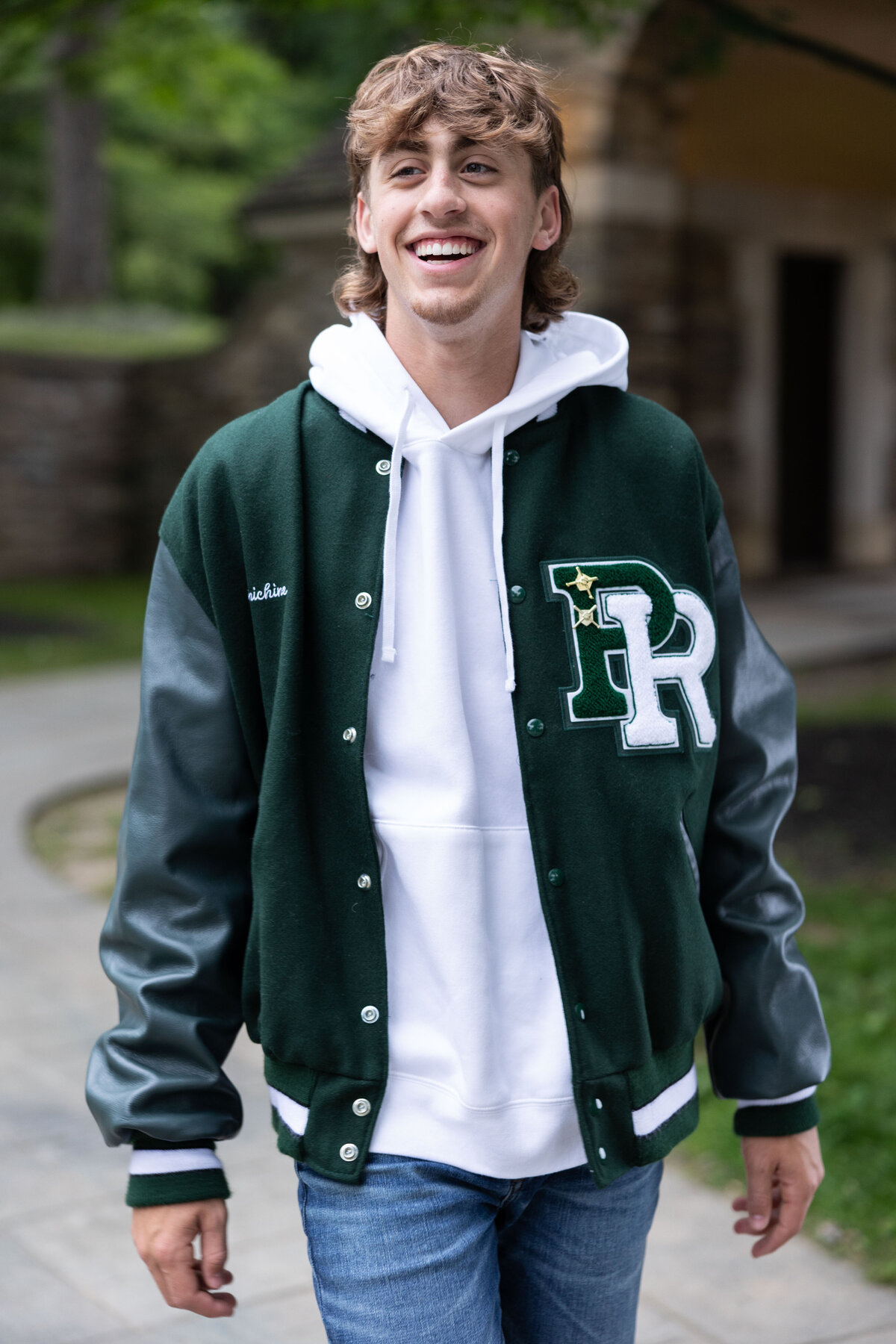 Pine Richland student walks smiling in his letterman jacket for Senior pictures.