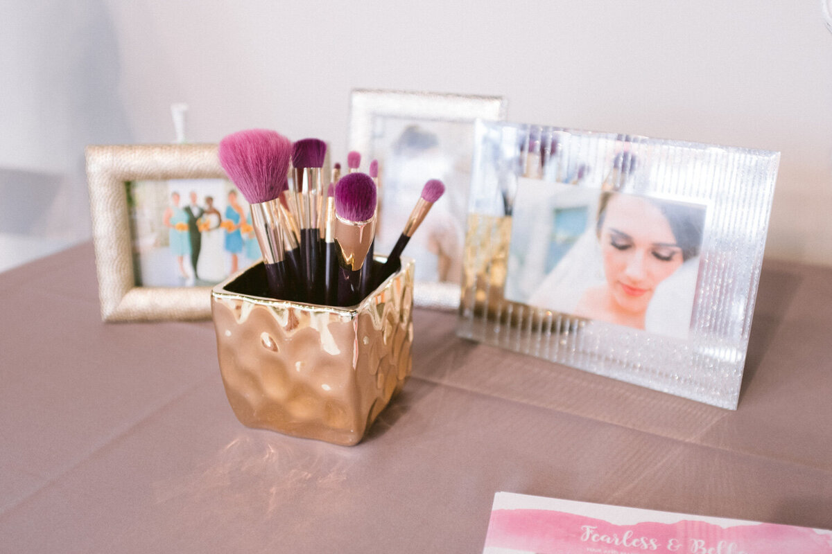 Table that has photo frames and a golden holder of make up brushes