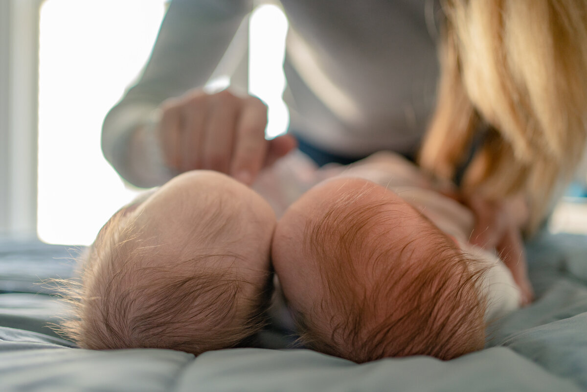 Twin babies laying next to each other only seeing the tops of their heads