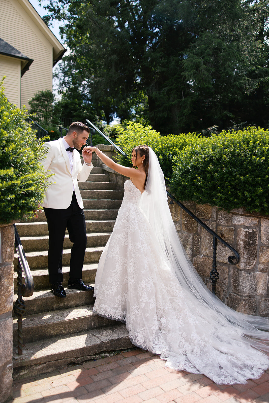 Groom kisses the bride’s hand on a stone staircase outside the church during their Highlands, North Carolina wedding.
