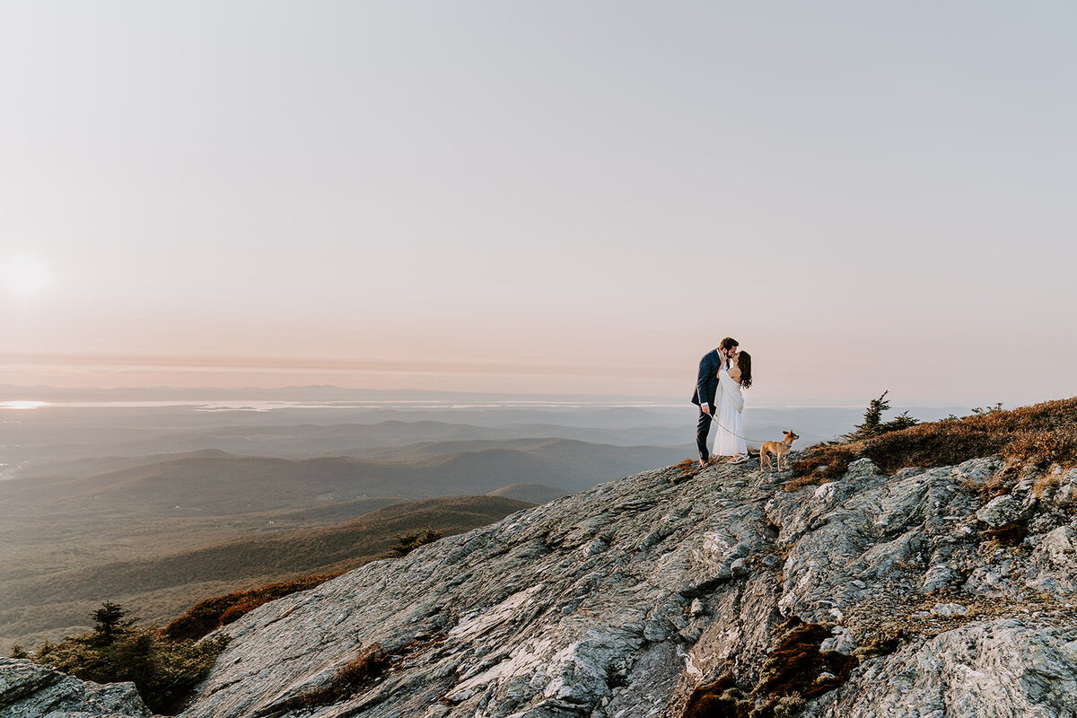 bride and groom kissing on top of mountain summit in Vermont