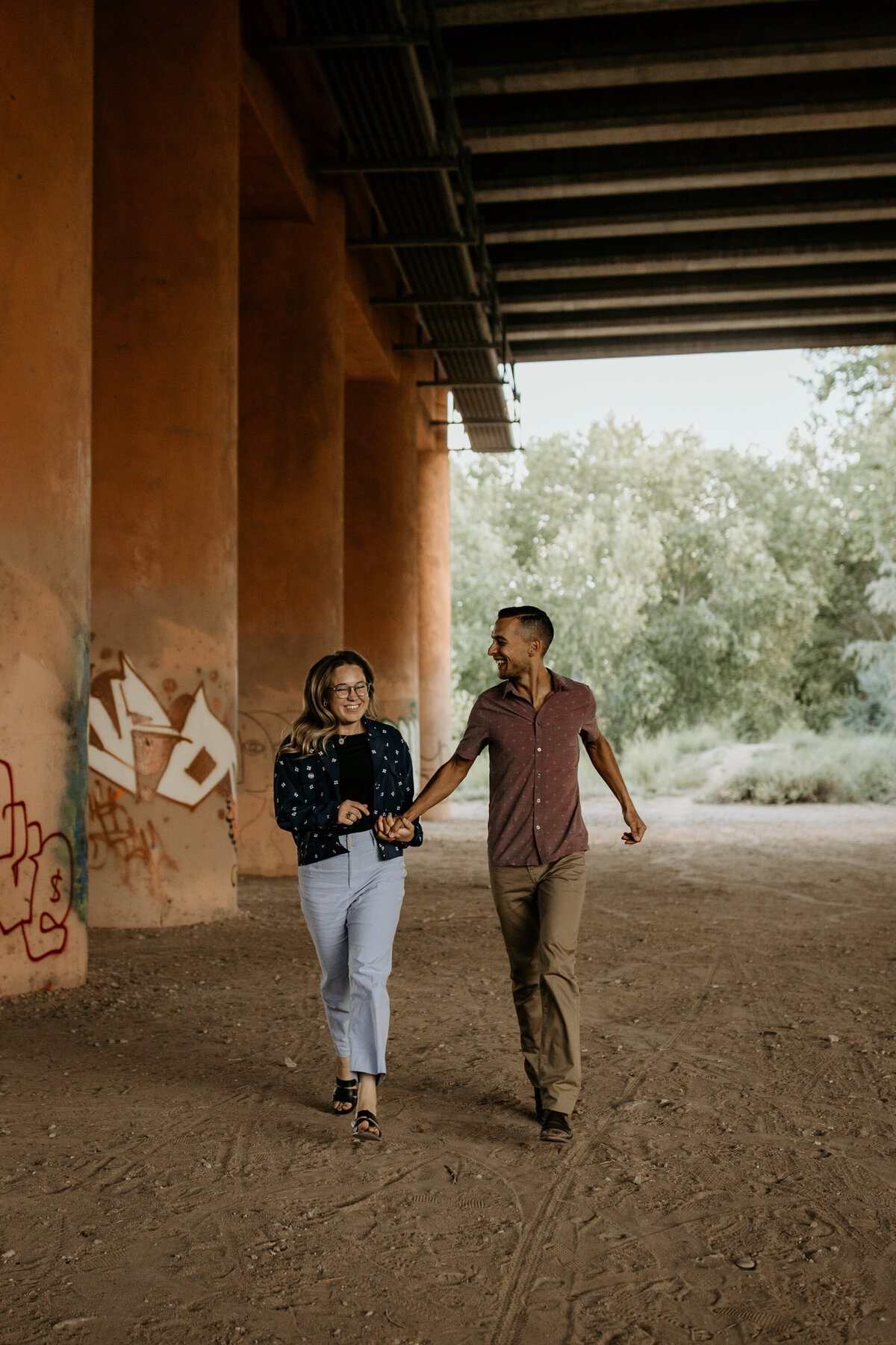 couple running together under an overpass in Albuquerque