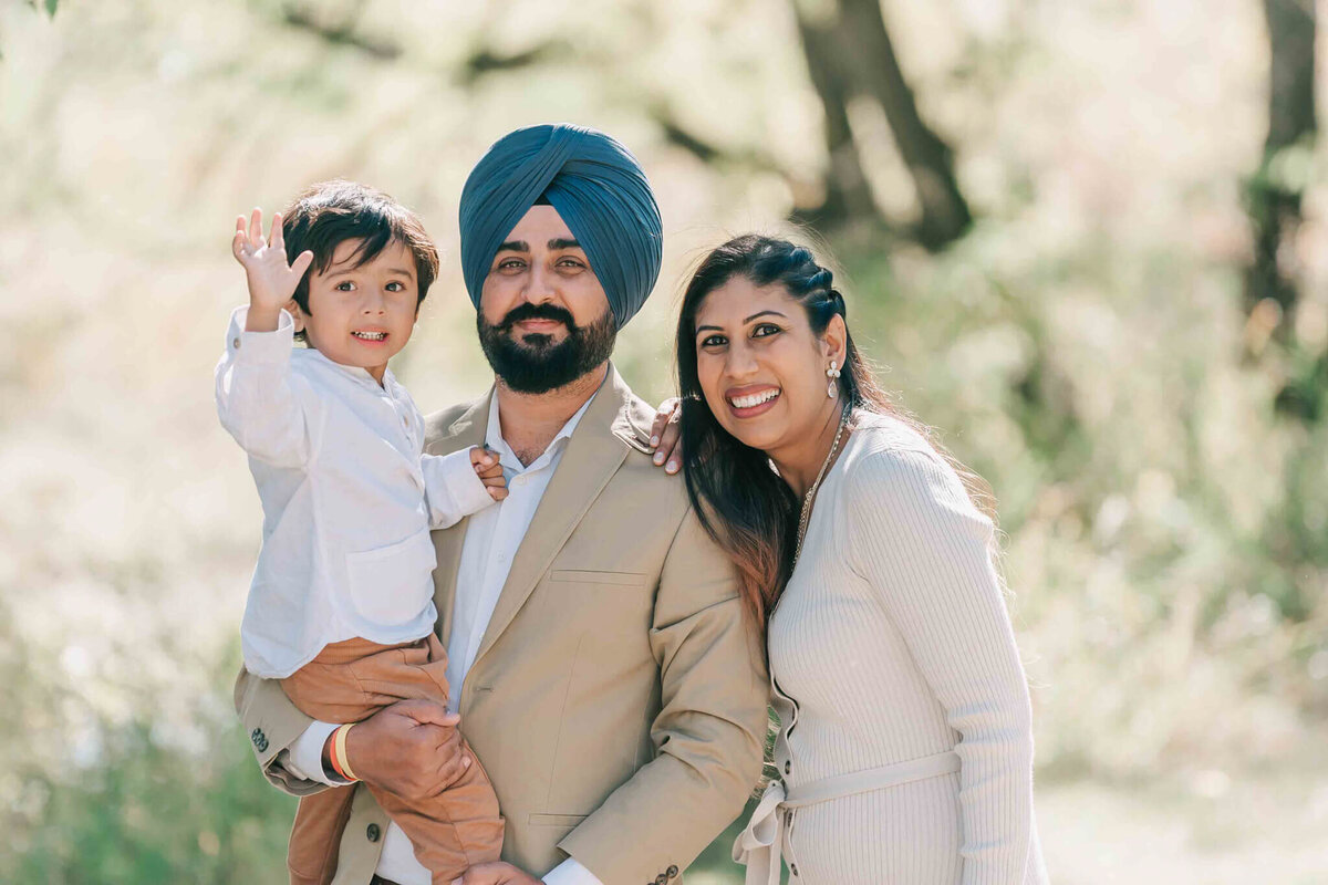 Dad holds son and mom stands in close. 