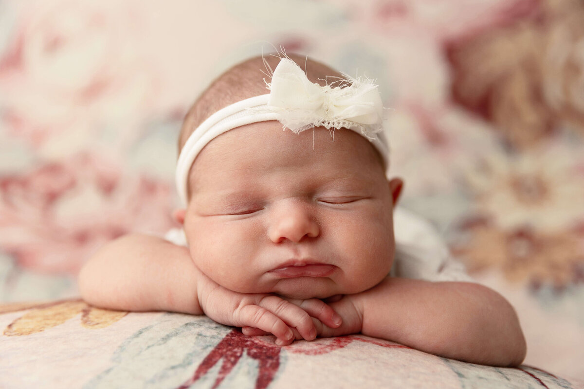 Newborn baby girl posed chin on hands in an Erie PA photography studio
