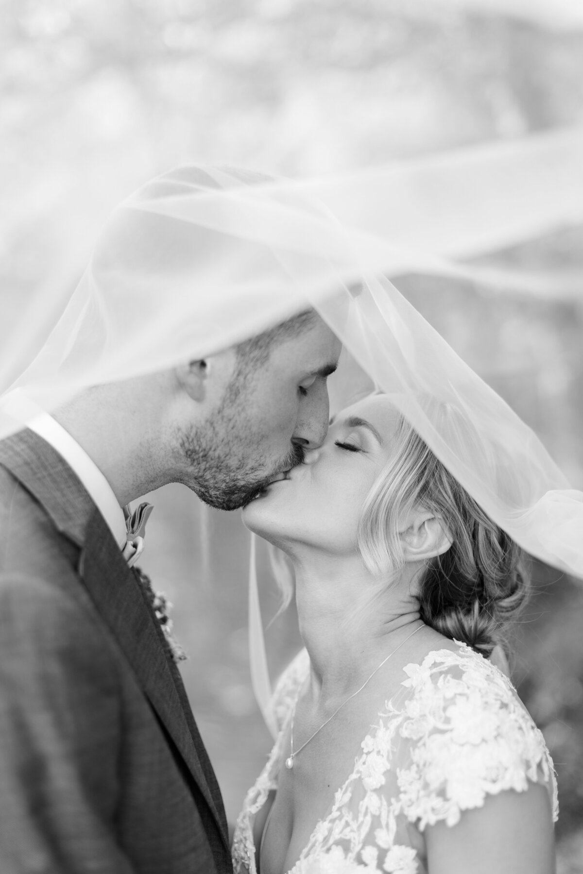 Bride and groom kiss under the bride's veil