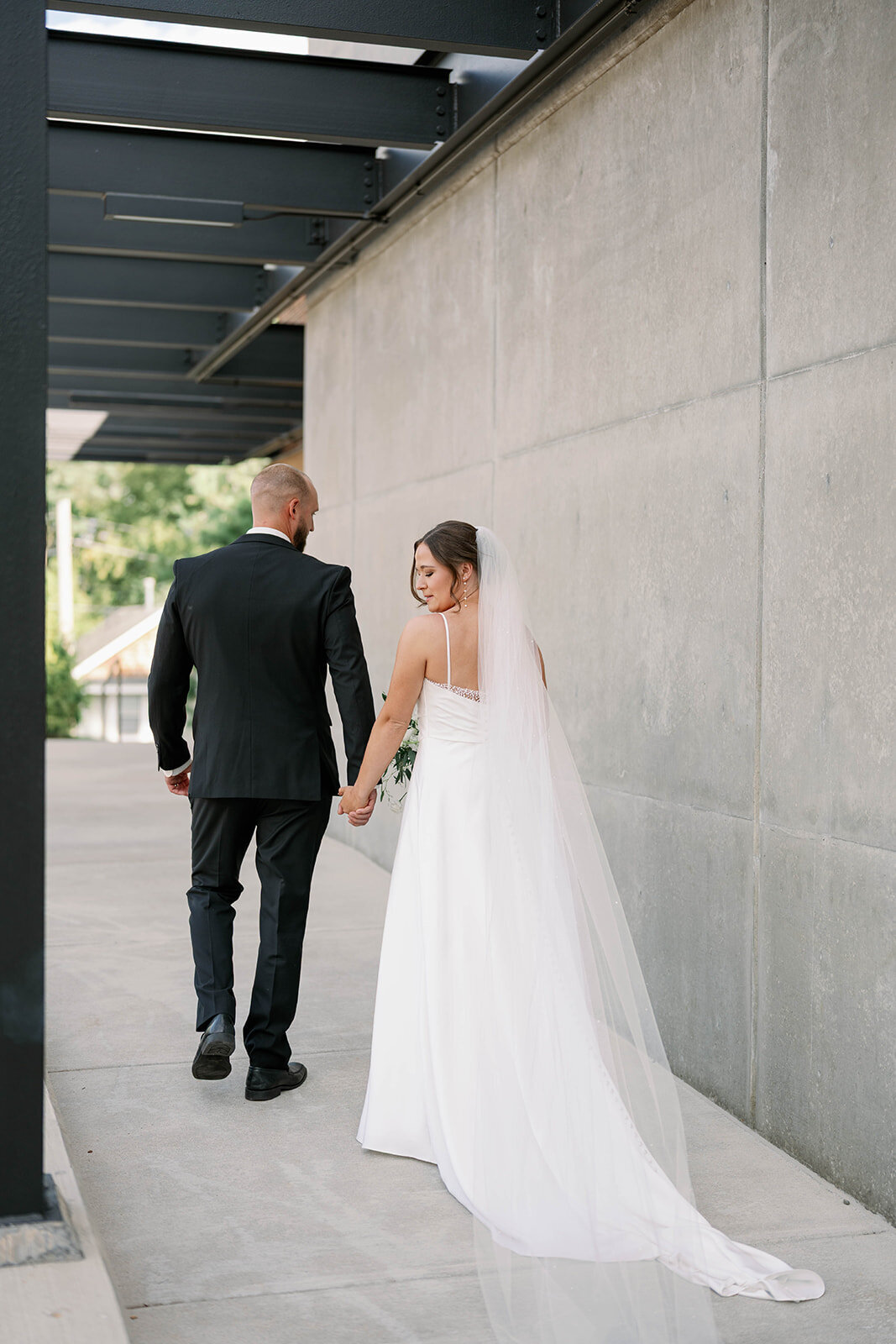 Bride looking over her shoulder as she and her groom walk into Leona Road Wedding Venue during their fall Grand Rapids wedding day.
