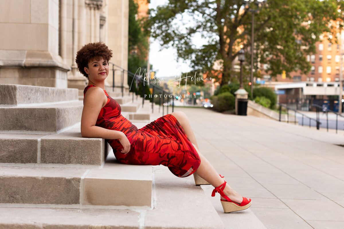 girl in red dress sitting on steps in Pittsburgh city.