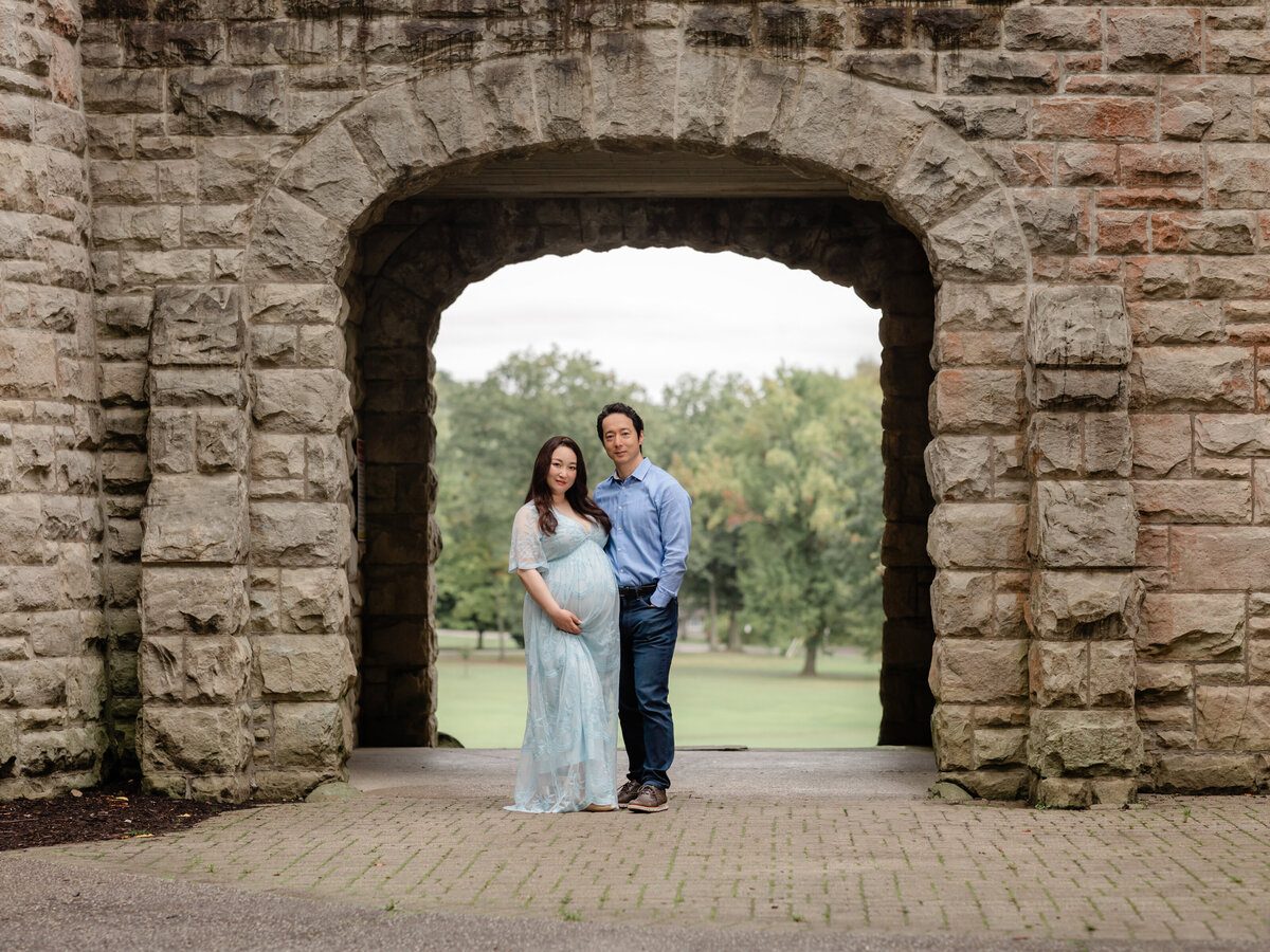 husband and pregnant mother in blue  lace gown holding belly for maternity portraits 