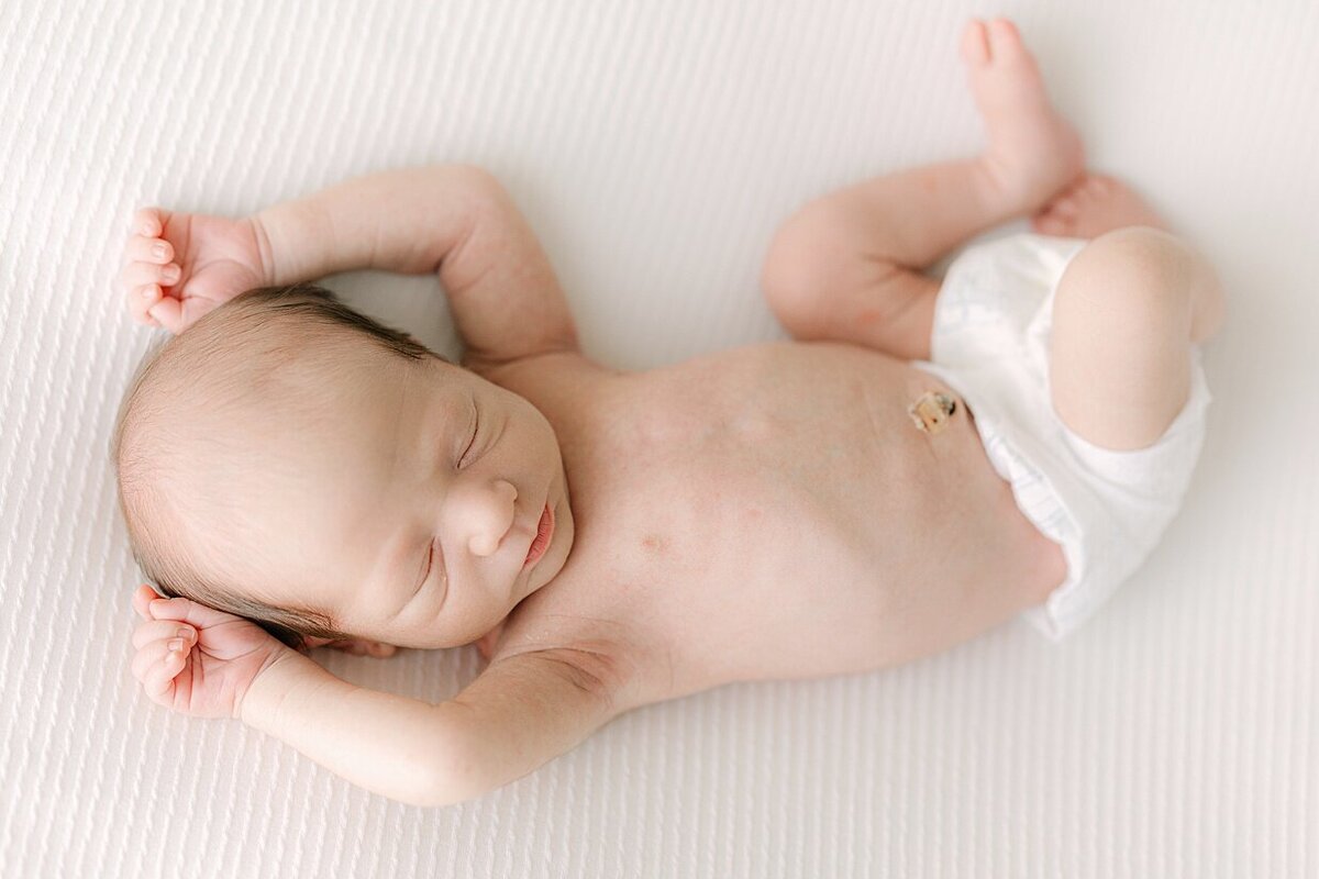 Newborn baby in a diaper sleeping with his arms above his head during a Indianapolis newborn photography session 