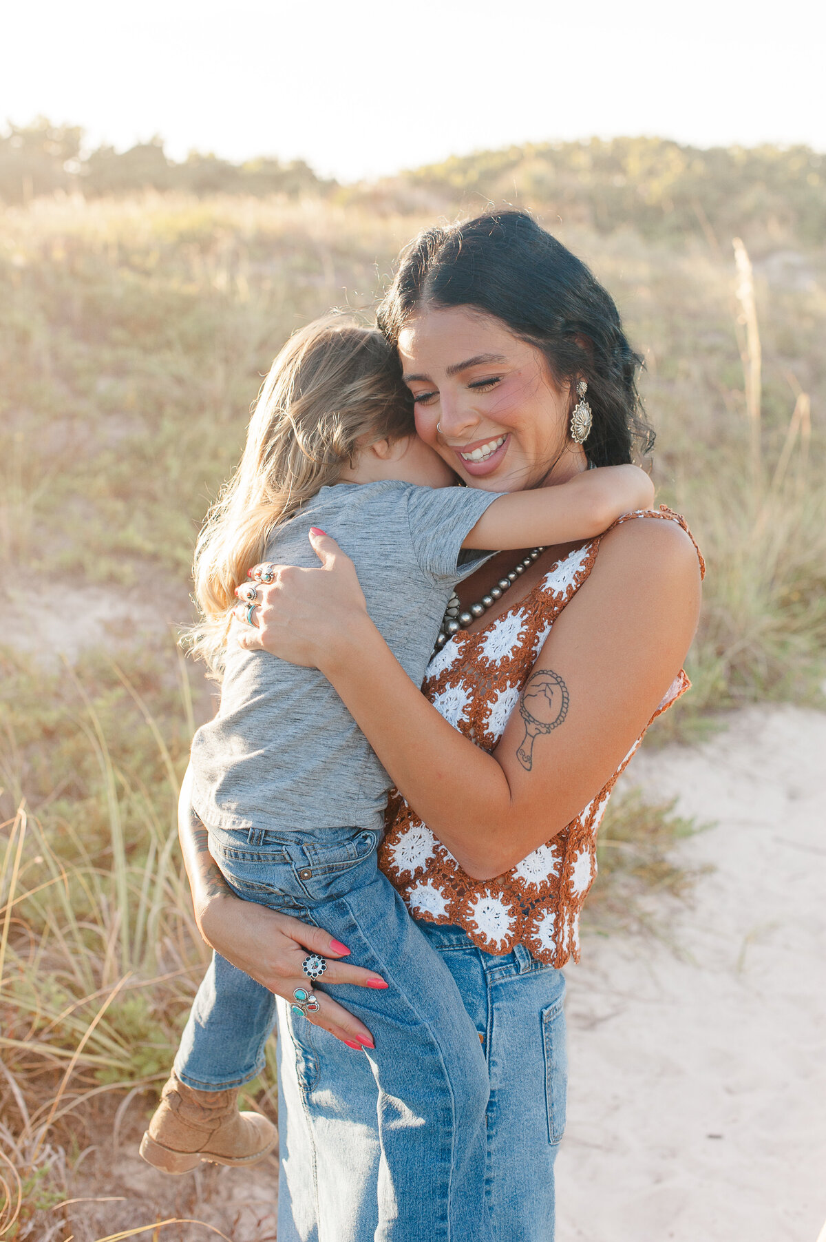 Mom holding son in the dunes at sunset