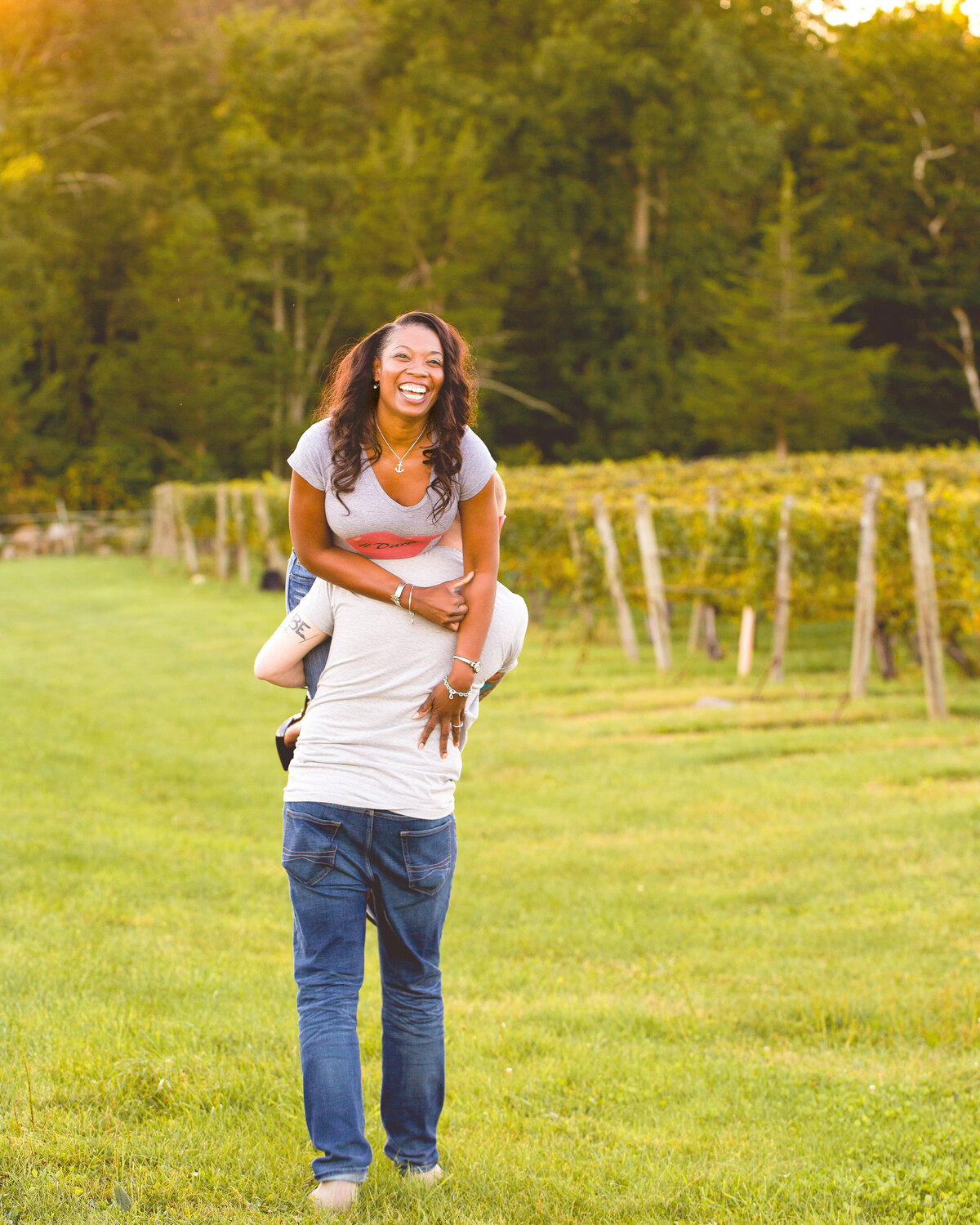 Woman laughs as her fiancé carries her over his shoulder.